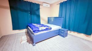 a small bed in a room with blue curtains at Ramana Suites in Berekum
