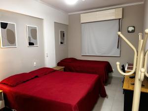 1 Schlafzimmer mit 2 Betten mit roter Bettwäsche und einem Fenster in der Unterkunft Cavalinho Branco in Águas de Lindóia