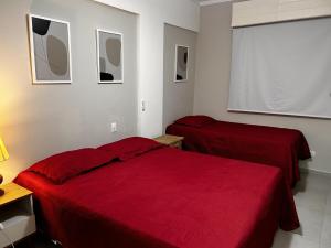1 Schlafzimmer mit 2 roten Betten und einem Fenster in der Unterkunft Cavalinho Branco in Águas de Lindóia