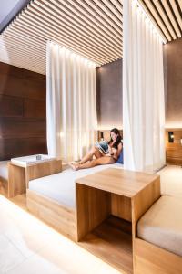 a woman sitting on a bed in a room at Alpen Hotel Post in Au im Bregenzerwald