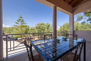 a balcony with a glass table and chairs on a porch at Olas y olivos in Akrotiri