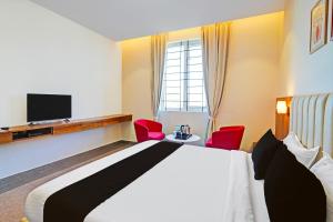 ニューデリーにあるHotel IVYのベッド1台と赤い椅子2脚が備わるホテルルームです。