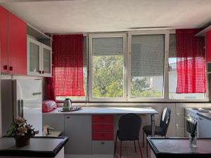 a kitchen with red windows and a kitchen counter with chairs at Klina Apartment in Skopje +8 photos
