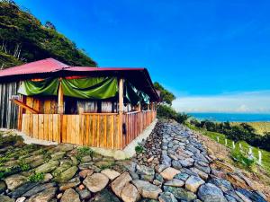 a building on a rocky hill with the ocean behind it at Ecolodge Maruamake in Santa Marta