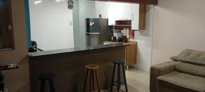 a kitchen with a counter with stools and a refrigerator at Casa do Caiçara in Ubatuba