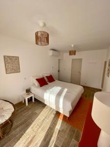 a bedroom with a large white bed with red pillows at Gîte "La petite pompe" avec piscine et spa in Prissac