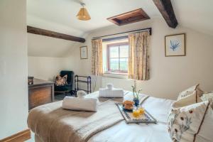 a bedroom with a bed with a table on it at Maple Cottage - Rural Charm & Cotswold Views in Dumbleton