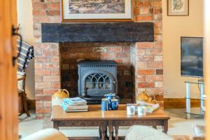 a brick fireplace with a table in a living room at Maple Cottage - Rural Charm & Cotswold Views in Dumbleton