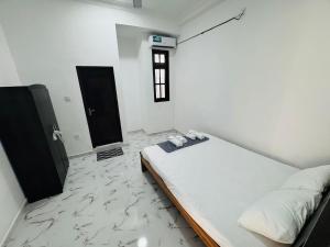 a white room with a bed and a black door at DP Aejis in Dehiwala
