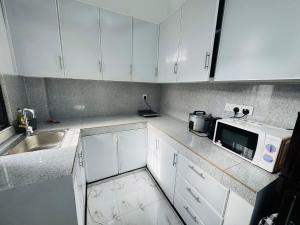 a kitchen with white cabinets and a sink and a microwave at DP Aejis in Dehiwala