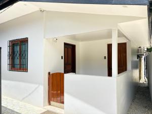 a white house with white walls and wooden doors at La Luna Inn El Nido in El Nido