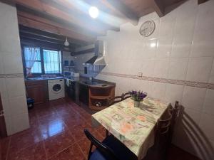 a kitchen with a table and a sink and a clock at La casina de la Texa in La Sestal