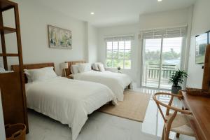 two beds in a white room with a window at no 185 hostel in Ban Pak Nam Pran