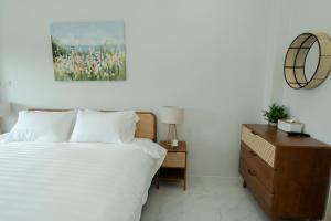 a bedroom with a white bed and a wooden dresser at no 185 hostel in Ban Pak Nam Pran