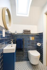 Spinney HillにあるNorthampton 3 Bed 3 Bathroom New Duplex Apartmentの青いタイル張りのバスルーム(洗面台、トイレ付) +9枚の写真
