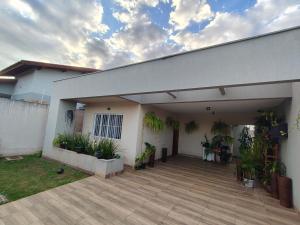 una casa bianca con patio con piante in vaso di Casa de 3 quartos com ares-condicionados a Campo Grande