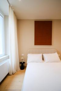 una camera da letto con un grande letto bianco e una finestra di Balcony Studio Double Suite - Bernina Experience a Tirano Altre 3 foto