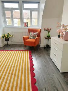 ロンドンにあるA vibrant placeのリビングルーム(オレンジチェア、ラグ付)
