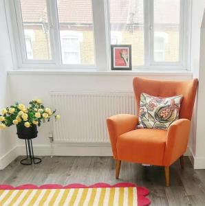 ロンドンにあるA vibrant placeの花瓶に花が飾られた部屋にあるオレンジ色の椅子