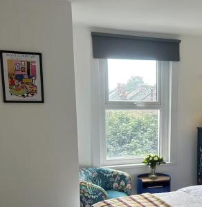 ロンドンにあるA vibrant placeの窓、椅子、ベッドが備わるベッドルーム1室が備わります。