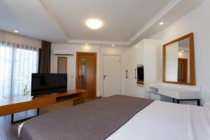 a bedroom with a large bed and a television at Kıvanç Suite Hotel in Bodrum City