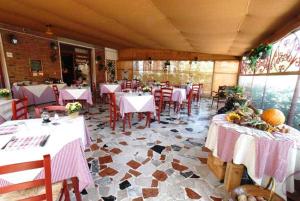 a restaurant with white tables and red chairs and a room with tables and chairsktop at Hotel Tarabaralla in Borgo a Buggiano