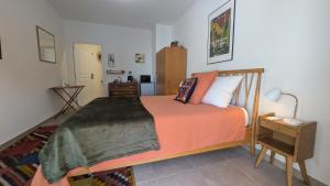 a bedroom with a bed with an orange comforter at Les Figuiers Sauvages Teyran in Teyran