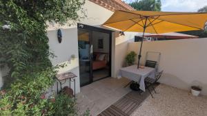 a patio with a table and an umbrella at Les Figuiers Sauvages Teyran in Teyran