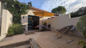 a patio with a table and an umbrella at Les Figuiers Sauvages Teyran in Teyran