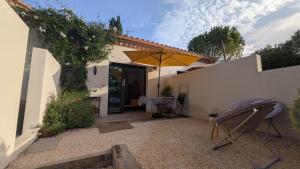 a patio with a table and an umbrella at Les Figuiers Sauvages Teyran in Teyran