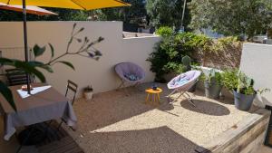 a patio with two chairs and a table with an umbrella at Les Figuiers Sauvages Teyran in Teyran +1 photo