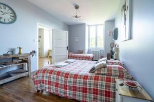 a bedroom with a bed and a clock on the wall at LE JARDIN SUSPENDU Domaine Le Carteron in Montfaucon