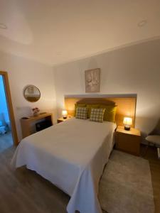 a bedroom with a large white bed and two lamps at Vivenda Por do Sol in Couço
