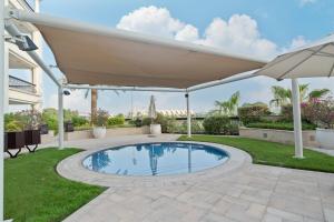 a patio with an umbrella and a swimming pool at Elegant Studio with Yas Views in Abu Dhabi