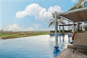 a pool at a resort with a palm tree at Elegant Studio with Yas Views in Abu Dhabi