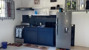 a kitchen with blue cabinets and a refrigerator at Glen Sea Inn in Port Maria