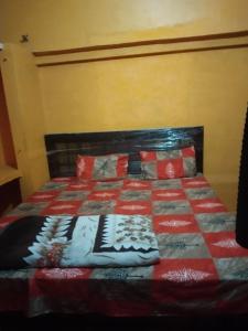 a bed with a red and white quilt on it at Radhika Yatri Nivas in Vrindāvan