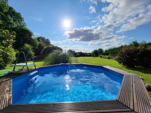 a swimming pool in a yard with a wooden deck at Maison Normande Charmante in Chamblac