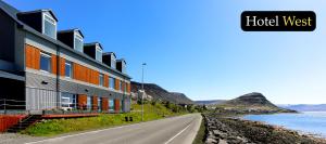 a building on the side of a road next to the water at Hotel West in Patreksfjörður