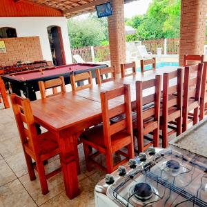 a kitchen with a wooden table with chairs and a pool at Chácara Vicente Gazzi in Socorro
