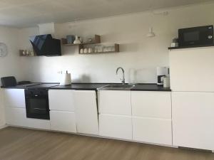 a kitchen with white cabinets and a sink at Hyggelig nyrenoveret lejlighed på landet - tæt på Hals og strand in Hals