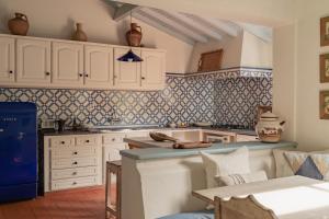 a kitchen with white cabinets and blue tiles at CABRA - Porto Covo in Porto Covo +40 photos