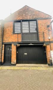 a brick house with two garage doors and a fence at The workshop in Kings Lynn