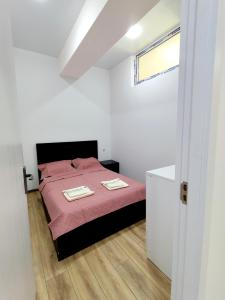 - une chambre avec un lit avec des draps roses et une fenêtre dans l'établissement Holbrook isani, à Tbilissi