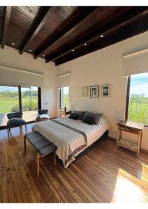 a bedroom with a large bed with two chairs and windows at Casa de Campo Familiar in Lobos