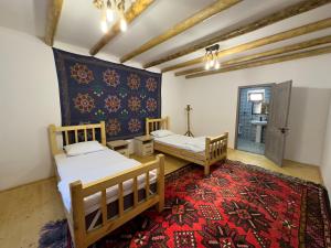 2 camas en una habitación con alfombra roja en Yulduz Homestay, en Sayyod