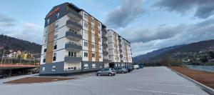 a large building with cars parked in a parking lot at Apartman Nia in Priboj