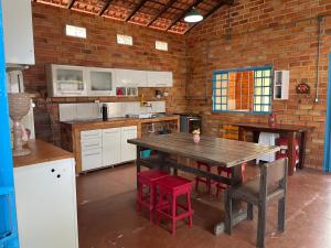 a kitchen with a wooden table and red chairs at Casa Arakyssawa in Salvaterra