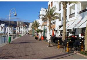 a sidewalk with chairs and palm trees and buildings at Appartement agadir centre in Agadir