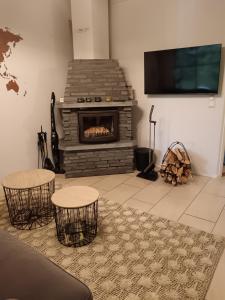 a living room with a fireplace with two chairs and a tv at Holiday Home Lumikieppi in Äkäslompolo